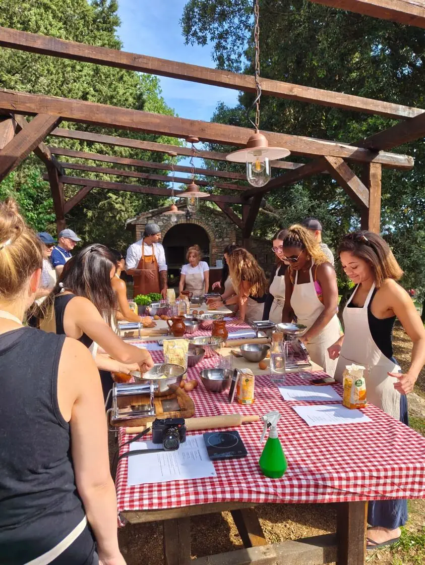 Guests hand-rolling fresh pasta together at a long outdoor table