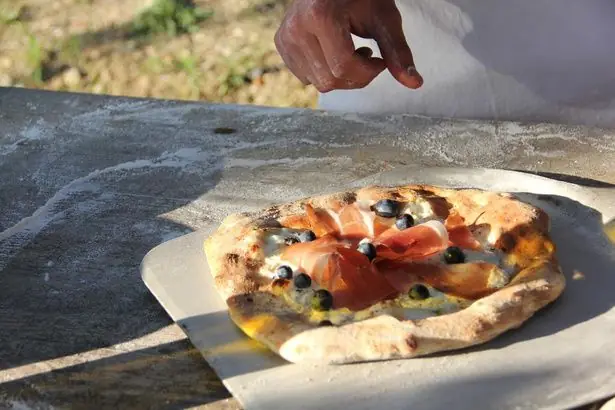 A wood-fired pizza fresh from the oven, topped with prosciutto